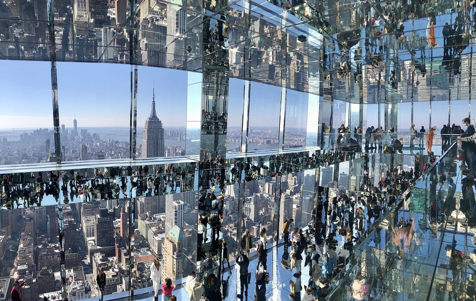 Visitors in SUMMIT's mirrored room with the Empire State Building beyond